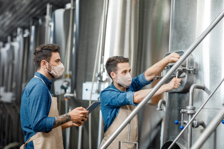 Brewery worker conducting safety inspection on brewing equipment
