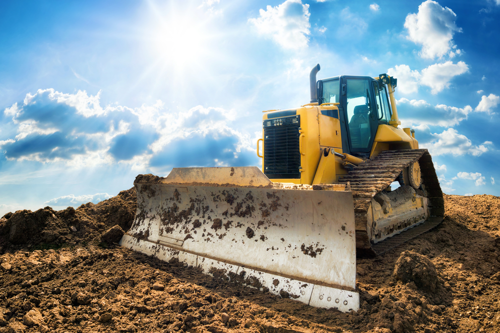 Technician performing bulldozer inspection checklist on heavy construction equipment
