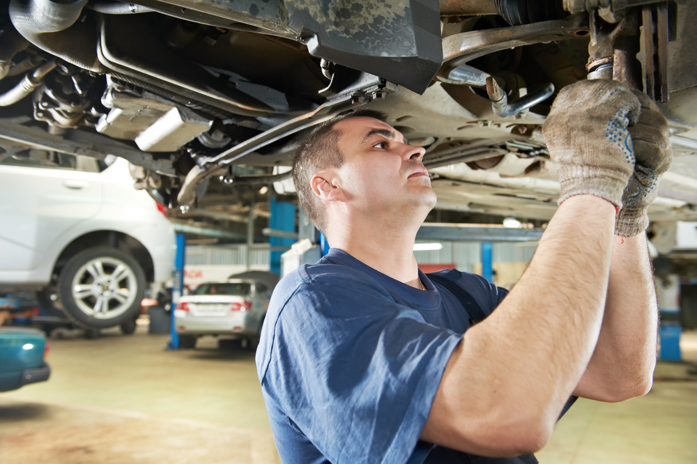 Mechanic inspecting a vehicle from underneath