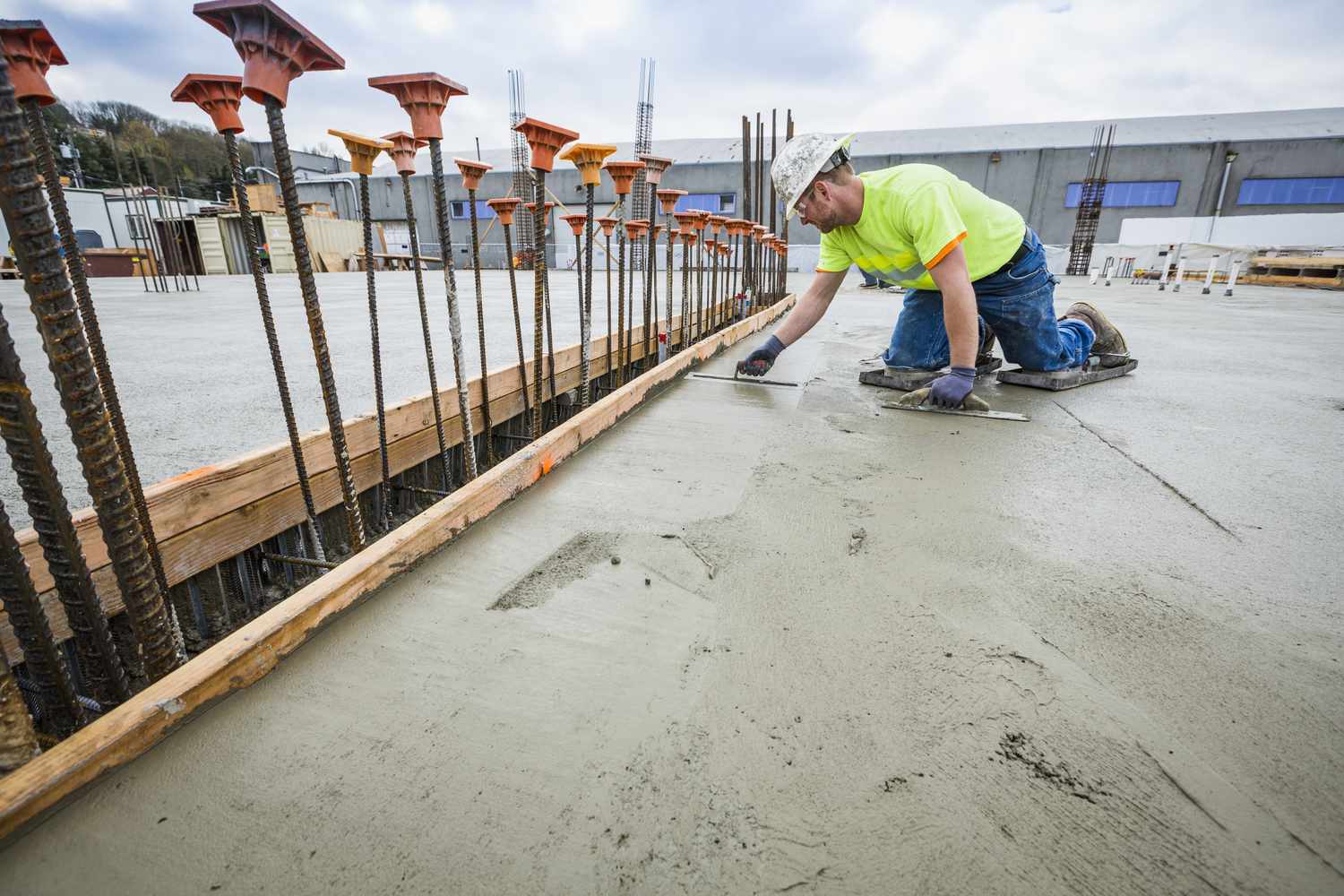 Workers inspecting a fresh concrete pour on a construction site